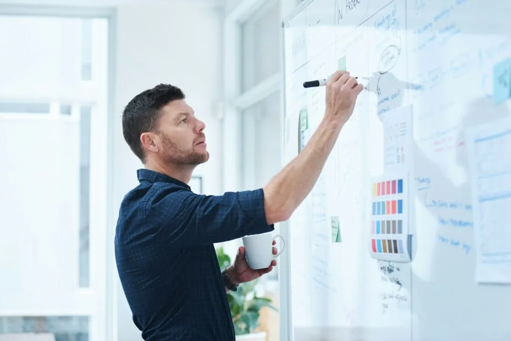 Shot of a handsome mature male designer working on a whiteboard in the office